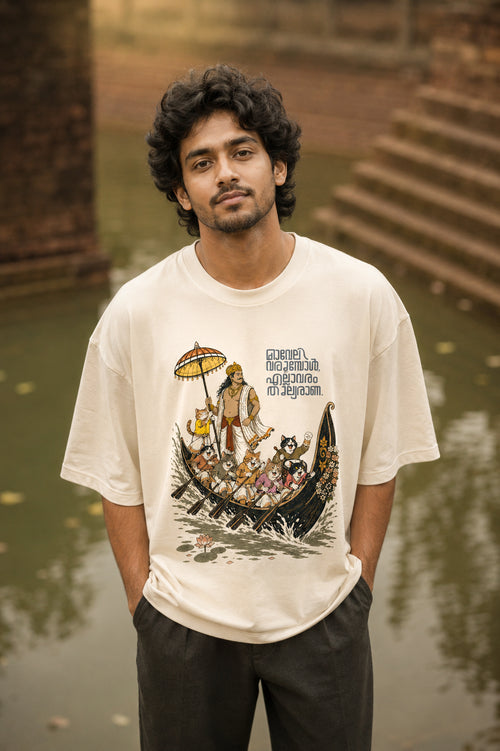 Model wearing Mild Popie's All Are Equal oversized graphic T-shirt featuring Mahabali, Kerala snake boat race, cats, and Indian dogs celebrating Onam.