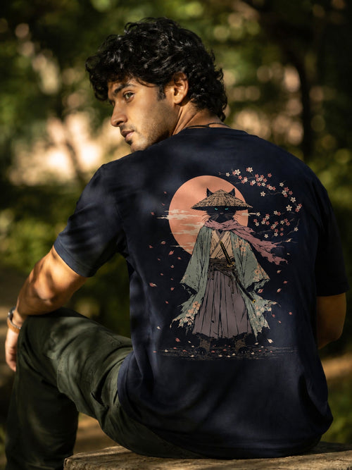 "Model wearing the Guardian Neko Japanese Cat Samurai regular fit t-shirt in navy blue featuring a cat samurai illustration with sakura petals and a rising sun on the back."